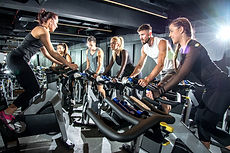 Group of sporty women and men training on exercise bikes together at gym..jpg